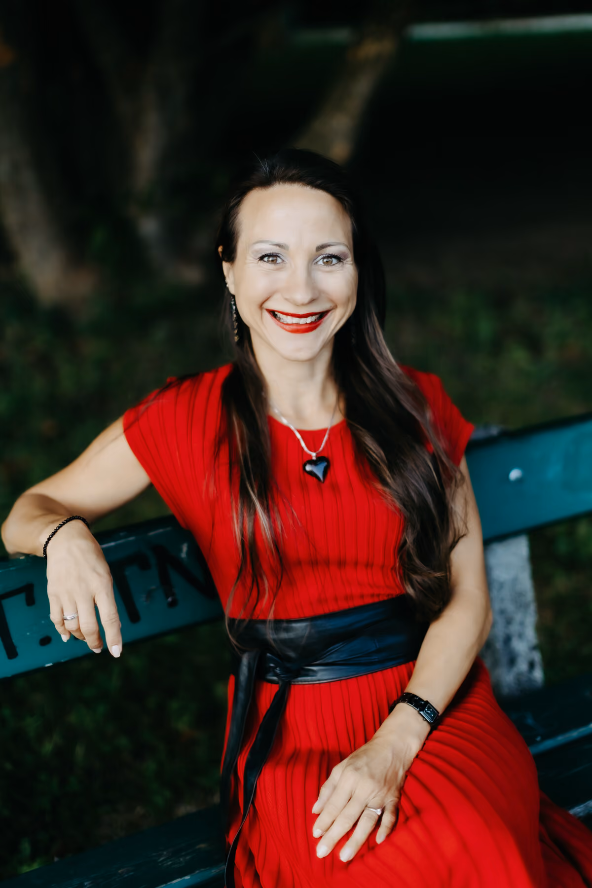 Maria Neuhuber im roten Kleid auf einer Bank